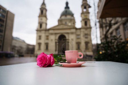 Téléchargez les photos : Une rose rose et une tasse à café sur une table devant la basilique - en image libre de droit