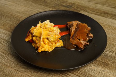 Fleischscheiben mit Macke und Käse auf einem schwarzen Teller