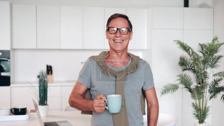 Téléchargez les photos : Portrait d'un homme mature à succès regardant la caméra et souriant et tenant une tasse de café ou de thé dans ses mains. - en image libre de droit
