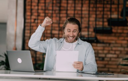 Photo for Overjoyed employee shows happines ove clenching fists looking in some documents or reports. Successful young entepreneur. - Royalty Free Image