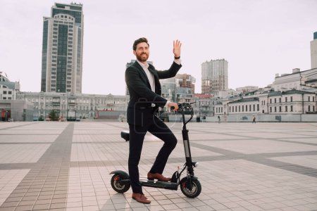 Foto de Joven hombre de negocios moderno en un traje montando una scooter eléctrica. Concepto de transporte ecológico. - Imagen libre de derechos