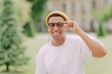 Téléchargez les photos : Portrait d'un jeune étudiant afro-américain élégant. Jeune homme joyeux portant des lunettes souriant à la caméra. - en image libre de droit