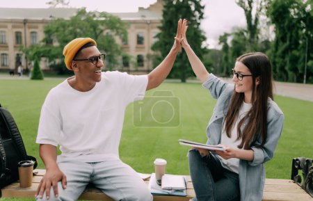 Photo for Two young people are studying together in university. Students outdoors giving five to each other - Royalty Free Image
