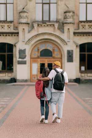 Photo for International students couple walking to the university building hugging each other, wearing stylish clothes. - Royalty Free Image