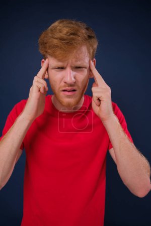 Téléchargez les photos : Jeune homme caucasien avec migraine isolé sur fond bleu touchant les tempes et ayant mal à la tête. isolé sur fond bleu - en image libre de droit