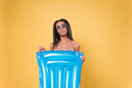 Téléchargez les photos : Sexy moitié nue afro-américaine femme se couvre avec un matelas gonflable. Concept vacances plage été. - en image libre de droit