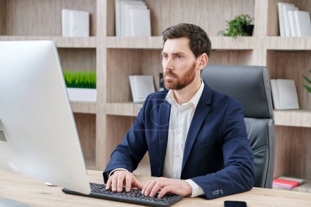 Foto de Guapo hombre de negocios maduro utilizando la computadora que trabaja en línea sentado en la oficina. escribir en el teclado en el lugar de trabajo - Imagen libre de derechos