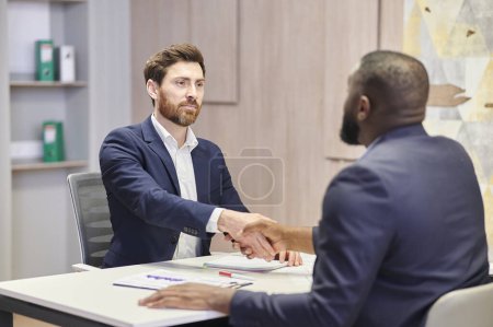 Photo for Positive closure of the business meeting. Interracial handshake and positive face expression. - Royalty Free Image