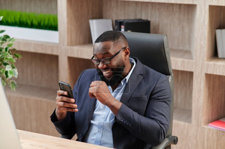 Photo for Excited happy african business man professional winner celebrate success read good news on smart phone feel overjoyed with mobile message online bet bid app game win looking at cellphone in office - Royalty Free Image