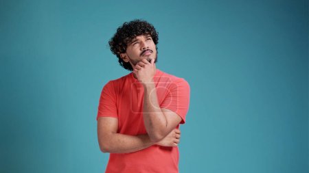 Téléchargez les photos : Latin espagnol homme en corail t-shirt sur fond bleu studio réflexion à la recherche d'une idée - en image libre de droit