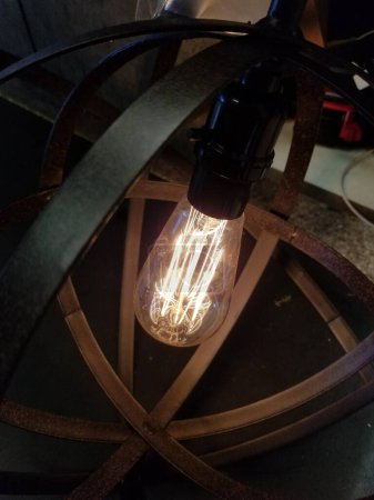 Téléchargez les photos : Ampoule Edison dans un cadre rond en métal noir. L'ampoule est allumée, fournissant une lueur lunaire. - en image libre de droit