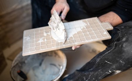 Tiler applying adhesive to a tile