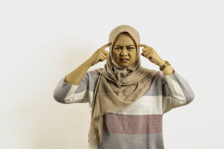 Foto de Mujer musulmana asiática que usa hijab o pañuelo en la cabeza pensando duro con el dedo tocando su templo. Mujer indonesia sobre fondo blanco. - Imagen libre de derechos