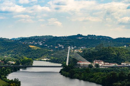 Scenery of Coimbra City in the summertime with the Mondego River and surrounding trees under a clear sky. Landscape background and wallpaper.