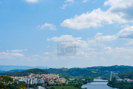 Scenery of Coimbra City in the summertime with the Mondego River and surrounding trees under a clear sky. Landscape background and wallpaper.