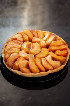 Téléchargez les photos : Une tarte aux pommes lorraine classique magnifiquement présentée sur une assiette noire. - en image libre de droit