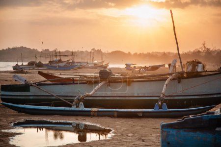Téléchargez les photos : Vieux bateau de pêche au coucher du soleil sur la plage au Sri Lanka - en image libre de droit