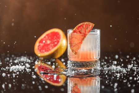 Photo for Light orange cocktail with a grapefruit slice and coarse sea salt on a mirror table with reflection - Royalty Free Image