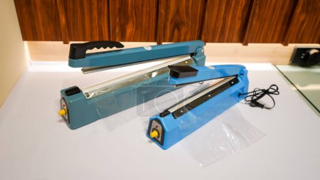 Photo for A plastic sealer is a small and handy tool designed to seal plastic bags in a quick and efficient manner. It works by heating up a wire or element that melts the plastic together, creating a strong and secure seal that prevents air or moisture from g - Royalty Free Image