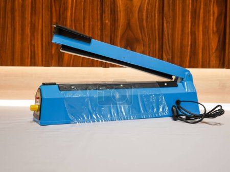 Photo for A plastic sealer is a small and handy tool designed to seal plastic bags in a quick and efficient manner. It works by heating up a wire or element that melts the plastic together, creating a strong and secure seal that prevents air or moisture from g - Royalty Free Image