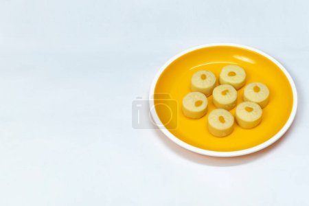 Indische Süßigkeiten (Bhalkoa) auf gelbem Teller auf weißem Hintergrund serviert,