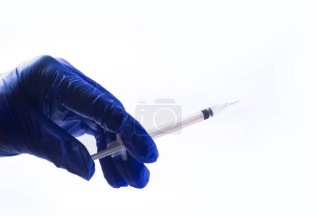 Foto de Mano del médico en guante azul sosteniendo una jeringa, aislada sobre fondo blanco. - Imagen libre de derechos