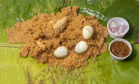 Téléchargez les photos : Biryani de poulet servi avec raita et oignons sur une feuille de banane. Un plat populaire indien non végétarien - en image libre de droit
