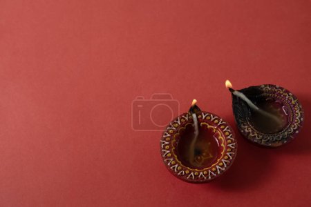 Photo for Happy Diwali and Kartika Deepam Festival Greetings - Colorful clay diya lamp on red background - Royalty Free Image