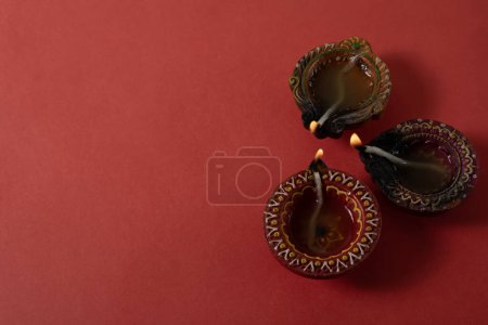 Photo for Happy Diwali and Kartika Deepam Festival Greetings - Colorful clay diya lamp on red background - Royalty Free Image