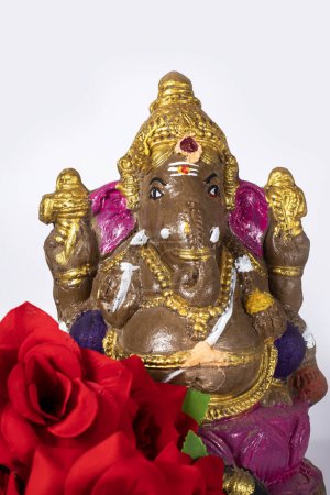 Foto de Ídolo de Ganesh hecho de arcilla con flor sobre fondo blanco. - Imagen libre de derechos