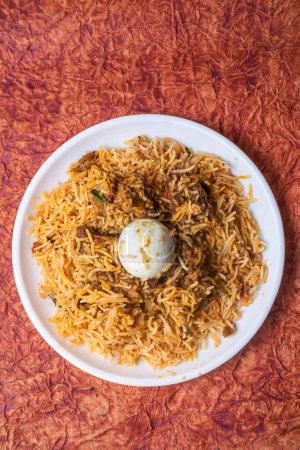 Indian Chicken Biryani dish is delicious and fragrant served on a white plate with egg in the middle top view.
