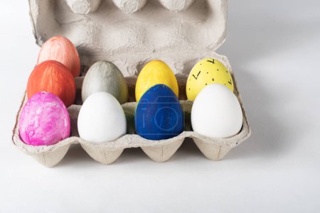 Photo for Colorful painted Easter eggs on a cardboard tray on a white background - Royalty Free Image