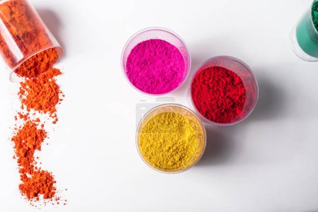 Colorful holi powder in glass jars on white background, top view