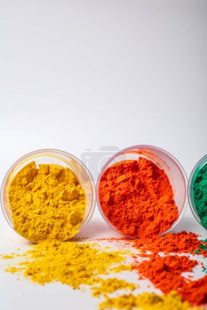 Colorful holi powder in a plastic containers on white background. Holi is Indian festival of colors