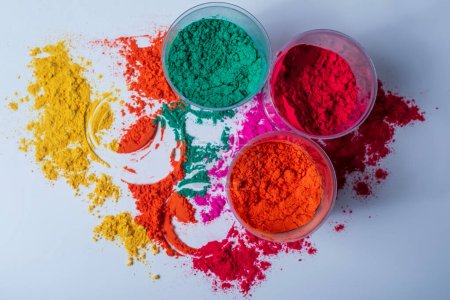 Colorful holi powder in plastic containers on a white background. Top view