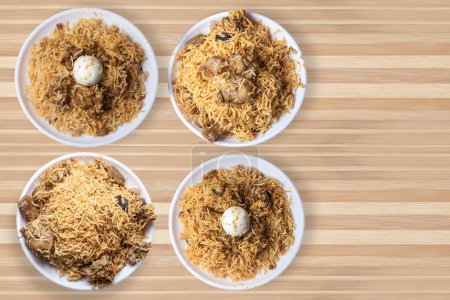 Set of popular biryani dishes on white plate on wooden table background. Chicken biryani, mutton biryani, egg biryani.