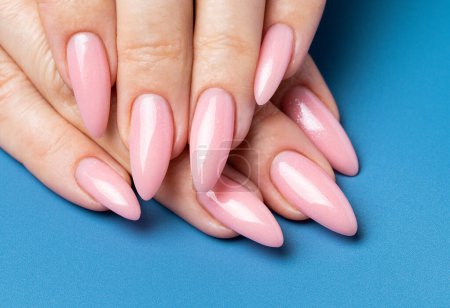 Téléchargez les photos : Elégant ongle tendance jeune femme mains manucure rose sur fond bleu - en image libre de droit