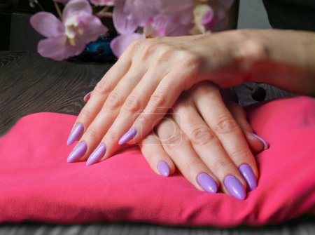 Foto de Elegante de moda uñas de mujer joven manos manicura violeta en el fondo. - Imagen libre de derechos