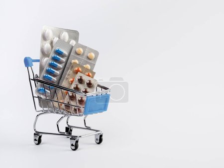 Photo for A supermarket trolley full of blister pills, a lot of pills in a wheelbarrow. Concept: home delivery of medicines.Empty space, a place for text, poster, board. Medical blue background. - Royalty Free Image