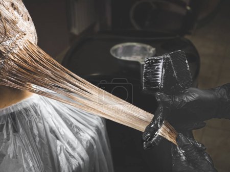 Photo for Close up of colorist dyes hair of woman with brush and foil in beauty salon - Royalty Free Image
