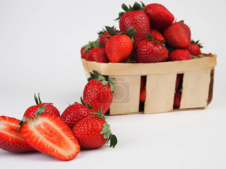 Téléchargez les photos : Panier plein de fraises rouges mûres luxuriantes avec des tiges en gros plan sur un fond vert de prairie printanière - en image libre de droit