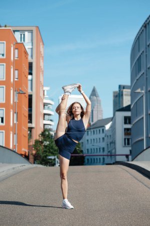 Foto de Mujer rubia flexible en ropa deportiva haciendo ejercicio de estiramiento. Deporte, estilo de vida activo, concepto de estilo de vida saludable - Imagen libre de derechos