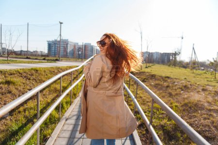 Téléchargez les photos : Vue arrière de caucasienne roux femme courant à l'extérieur et regardant la caméra. Concept d'été et de personnes - en image libre de droit