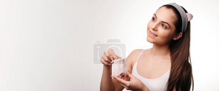 Téléchargez les photos : Femme heureuse souriante tout en tenant paquet avec des capsules d'acides gras oméga 3. Femme gaie utilisant des suppléments nutritionnels dans le cadre d'une routine d'autosoin saine - en image libre de droit
