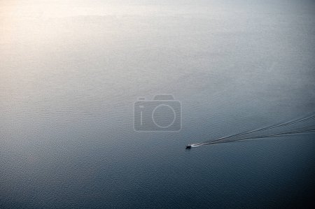 Photo for Modern moving boat floating fast on sea and leaving splashes on water surface. Calm atmosphere among beautiful landscape. - Royalty Free Image
