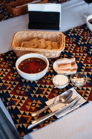 Téléchargez les photos : Bortsch ukrainien à la crème sure poivre à l'ail et sauce debout à la table. Café fond. Concept alimentaire - en image libre de droit