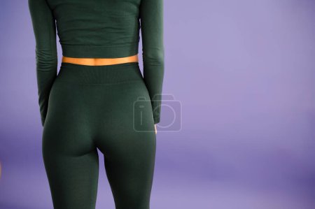 Photo for Cropped close up view photo of sexual sporty sportive tempting beautiful attractive nice round ass wearing green tight pants leggings. Violet background - Royalty Free Image