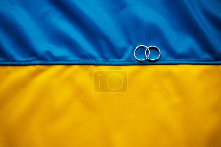 Téléchargez les photos : Mariage pendant la guerre. Deux alliances sont superbement disposées sur le drapeau ukrainien. Soutien à l'Ukraine et au peuple - en image libre de droit