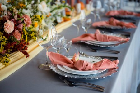 Foto de Elegante mesa festiva con platos de lujo, vasos, cubiertos y servilletas. Hermosos ramos de flores para la decoración de todo. Boda de diseño e idea. - Imagen libre de derechos