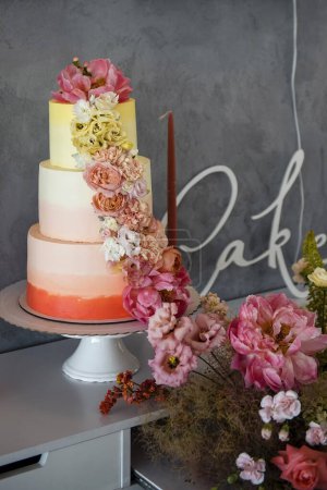 Foto de Pastel de boda de tres capas decorado con crema de colores y hermosas flores frescas. Panadería artesanal única. Increíble diseño e idea de postre. - Imagen libre de derechos
